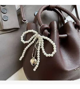 Detailaufnahme der schokoladenbraunen Ledertasche mit Perlenbogen und Herzanhänger
