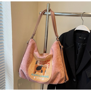 Detail of pink corduroy tote bag featuring cat embroidery and brown leather handles