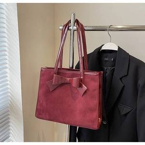 Close-up of wine red suede tote bag featuring a large decorative leather bow detail