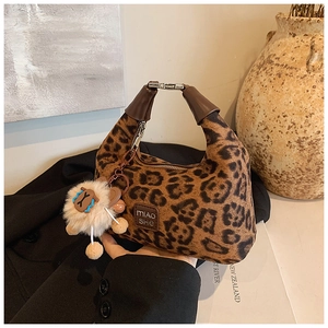 Detailed leopard print bag with leather handle and decorative plush sheep pendant detail