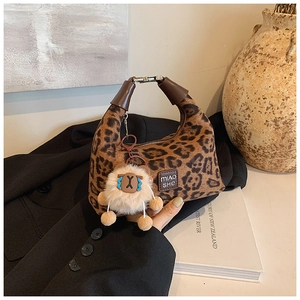 Detail of leopard print crossbody bag with plush sheep charm and brown handle