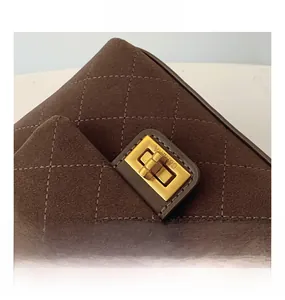 Close-up of quilted suede texture and gold metal turn-lock on the brown crossbody bag