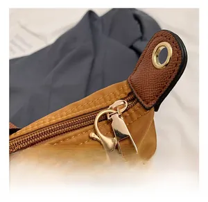 Close-up of golden hardware and contrast leather trim on a durable nylon tote bag