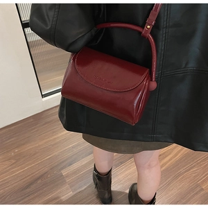Detail of burgundy PU leather crossbody bag with top handle and sleek shoulder strap