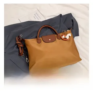 Close-up of ginger nylon tote bag featuring leather handles and a horse pendant detail