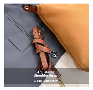 Detail view of the yellow tote bag featuring an adjustable brown leather strap with gold buckles