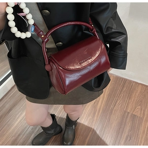 Detail of burgundy patent leather handbag featuring unique circular rigid top handle