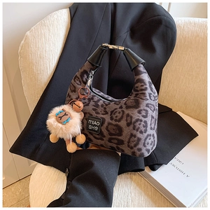 Detail of leopard print crossbody bag with plush charm and silver zipper closure