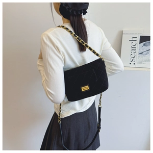 Detail of black quilted velvet bag featuring a gold twist lock and chain strap