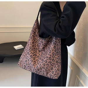 Close-up of a large leopard print hobo bag with a black strap worn by a model