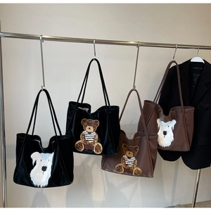 Detail of large tote bags showing bear and puppy plush patches on smooth leather