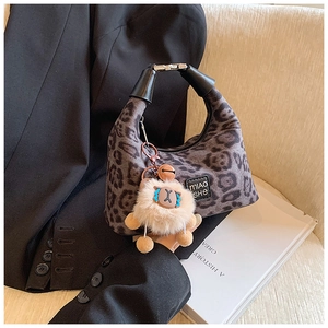 Leopard print hobo bag with silver buckle and plush sheep charm on lifestyle background