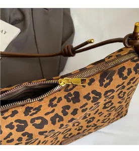 Close-up of leopard print tote bag featuring a smooth gold zipper and striped inner lining