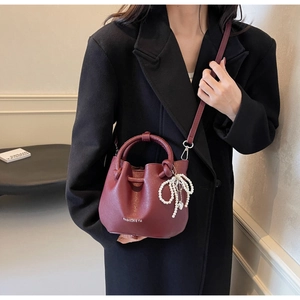 Detailansicht der weinroten Leder-Eimertasche mit Perlen-Schleife und Tragegriff