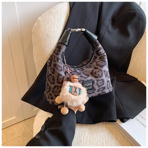 Detail of leopard print crossbody bag with cute plush bear charm on white chair