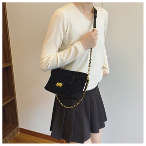 Close-up of black quilted velvet crossbody bag with gold chain strap on a model