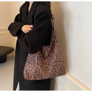 Detailed side view of a large leopard print tote bag paired with a black wool coat