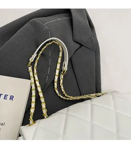 Detailed view of cream quilted shoulder bag with chain strap on a grey blazer
