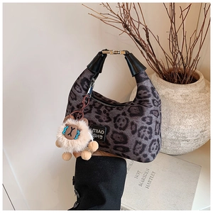 Detail of leopard print crossbody bag with black leather handle and beige plush lamb charm