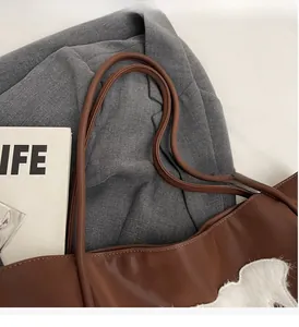 Detail of reinforced smooth PU leather handles on a large brown minimalist tote bag