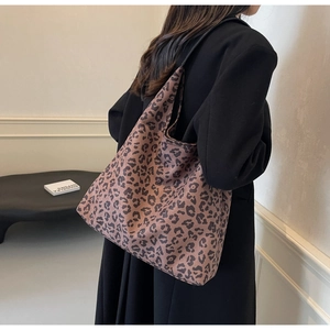Detail of a large leopard print tote bag styled with a long black winter coat