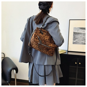 Sac bandoulière léopard avec poches zippées porté sur un tailleur pantalon gris