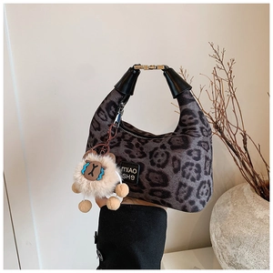 Detail of leopard print crossbody bag with golden buckle and cute plush charm