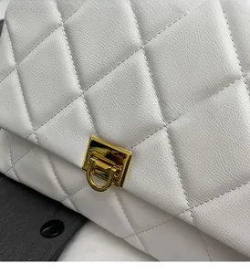 Close-up of white quilted leather texture and golden rectangular metal buckle on handbag