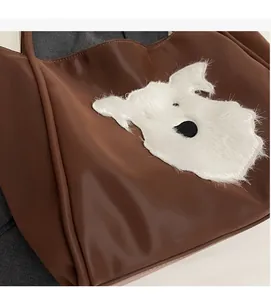 Detail of soft brown tote bag with white plush dog patch and smooth leather texture