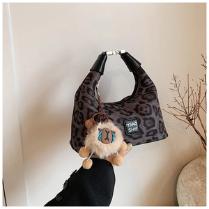Detail of leopard print hobo bag with silver buckle and plush sheep charm accessory