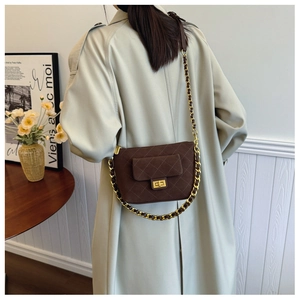 Brown faux suede crossbody bag with gold twist lock and chain strap on trench coat