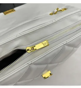 Detailed macro shot of a white quilted leather bag with smooth golden metal zipper and chain