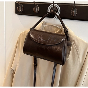 Close-up of a vintage dark brown leather crossbody bag with embossed GUEAROO logo