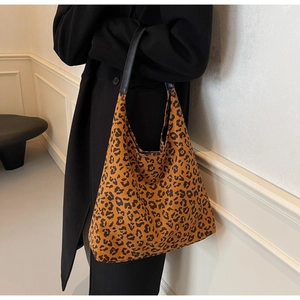 Close-up of leopard print hobo tote bag with black leather strap and soft fabric texture