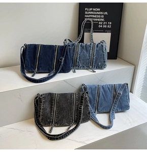 Detail of four vintage denim crossbody bags in varied washes on marble steps