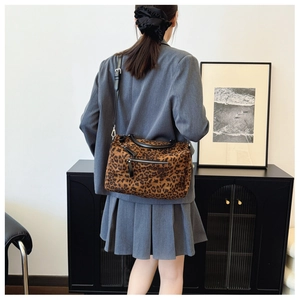 Détail du cabas à imprimé léopard avec poignées en cuir noir et poche zippée pratique