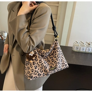 Close-up of leopard print tote bag with leather knotted strap and plush monster charm
