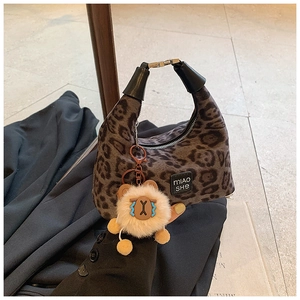 Detail of leopard print handbag featuring plush texture, leather handle and lion charm
