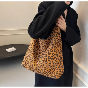 Detailed view of oversized leopard print tote bag styled with a classic black winter coat