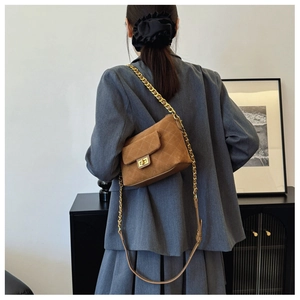 Detailed close-up of brown quilted faux suede crossbody bag with golden chain strap