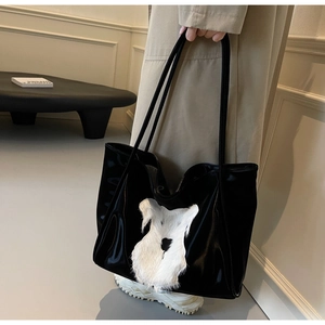 Side view of black glossy tote bag with plush white schnauzer motif and long straps