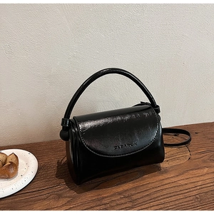 Macro shot of glossy black leather handbag with a round top handle and Clearok logo