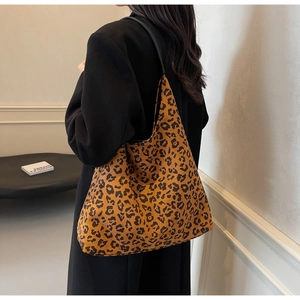 Detail of a large leopard print tote bag with black strap worn by a model in a casual style