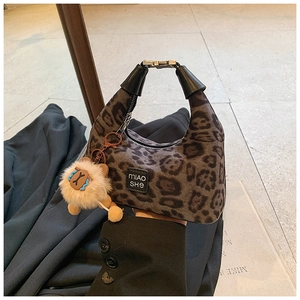 Detail of leopard print crossbody bag with cute lion plush charm and brand logo