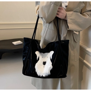 Detail of glossy black tote bag with white plush schnauzer appliqué and long handles