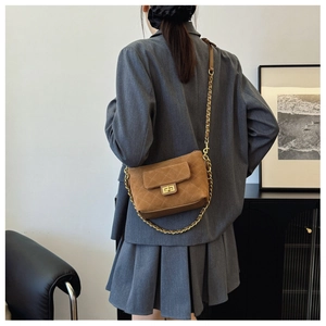 Detail of brown quilted suede shoulder bag featuring gold twist lock and chain strap