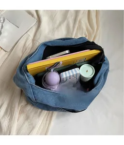 Detail showing high-capacity denim tote bag interior with umbrella, books, and phone