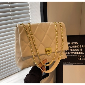 Detail der weißen Stepptasche mit goldenem Drehverschluss und Metallkettenriemen