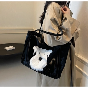 Detail view of large black patent leather tote bag with plush white schnauzer puppy patch