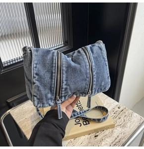 Detail view of washed denim crossbody bag featuring double vertical silver zippers